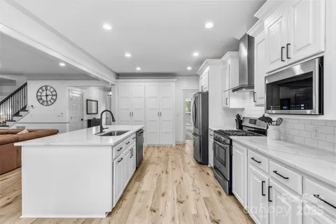 a kitchen with stainless steel appliances granite countertop a sink and a stove top oven with wooden floor