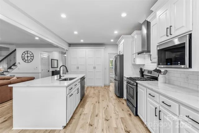 a kitchen with stainless steel appliances granite countertop a sink and a stove top oven with wooden floor