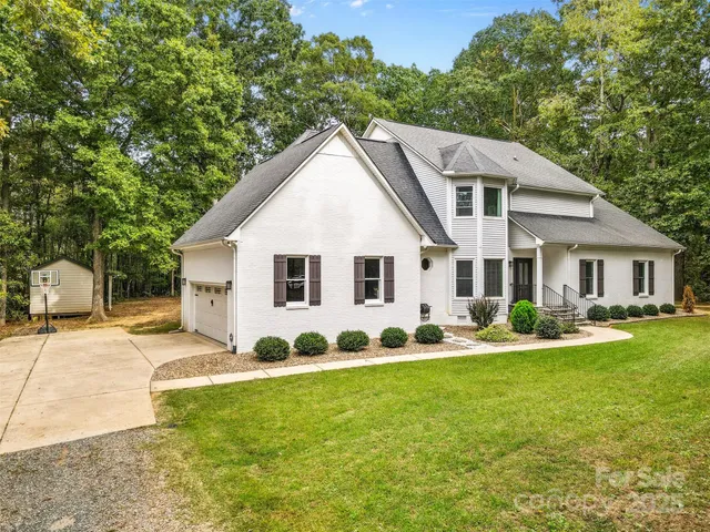 a view of a white house with a yard and sitting area