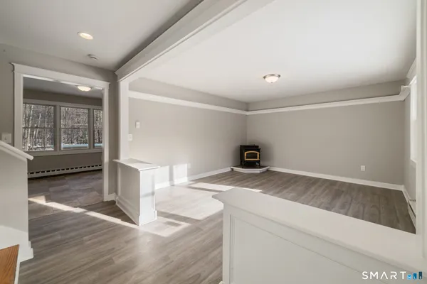 a view of an empty room with a window and wooden floor