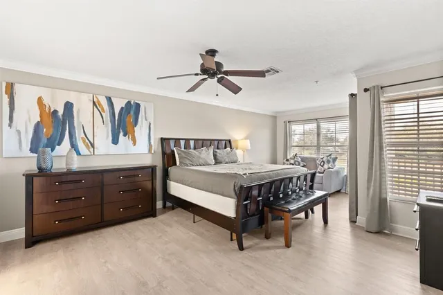 a bedroom with a bed a dresser and a chandelier