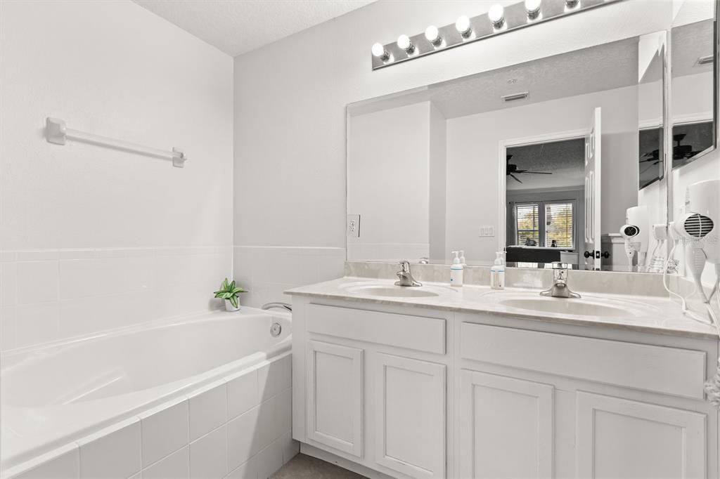 856 Assembly Court Reunion, FL 34747 - Photo 21 of 37 a bathroom with a tub a sink and mirror