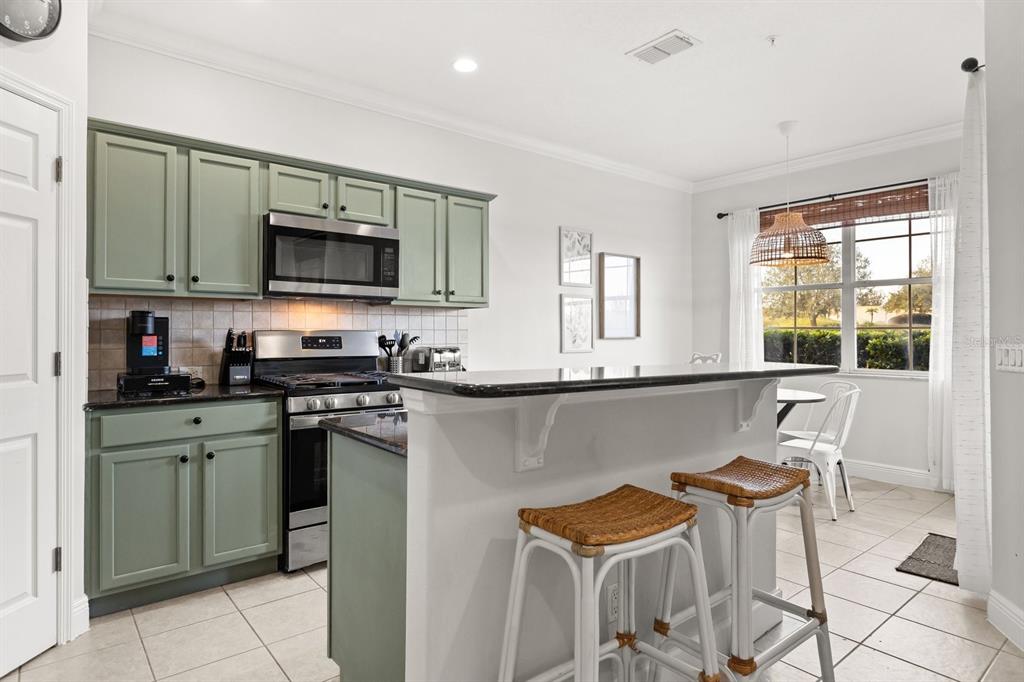 856 Assembly Court Reunion, FL 34747 - Photo 8 of 37 a kitchen with stainless steel appliances kitchen island granite countertop a sink and a stove top oven