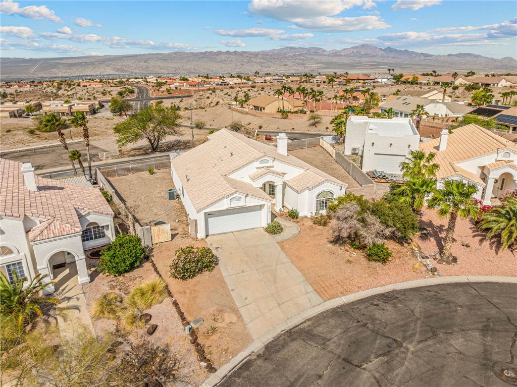 2853 Winchester Road Bullhead City, AZ 86442 - Photo 38 of 40 The property features a light-colored exterior, a driveway leading to a two-car garage, and a tiled roof