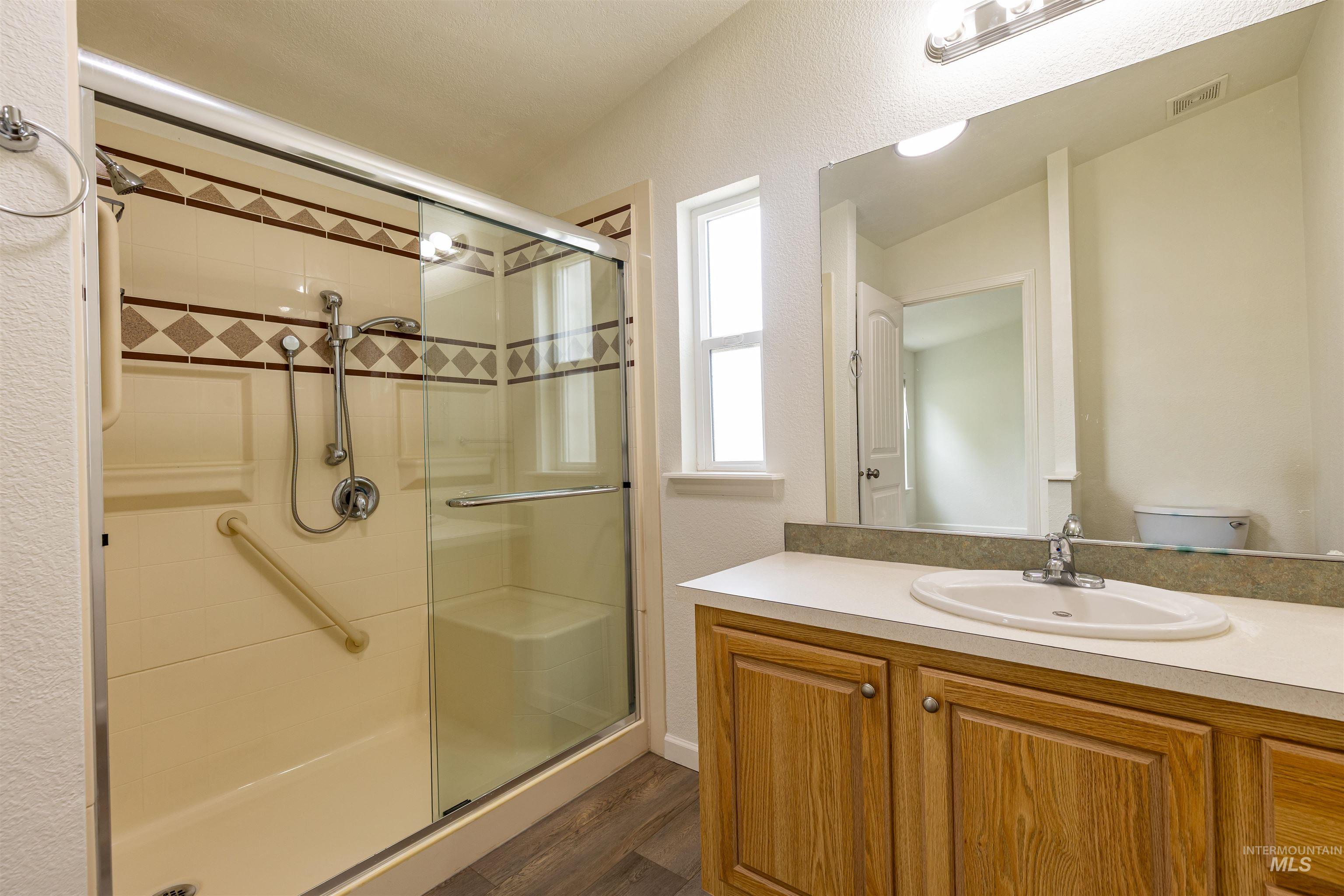 17028 Lower Pleasant Ridge Road Caldwell, ID 83607 - Photo 11 of 21 Bathroom featuring a shower with glass enclosure, a built-in bench, and a handheld showerhead