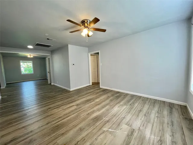 a view of empty room with wooden floor and fan