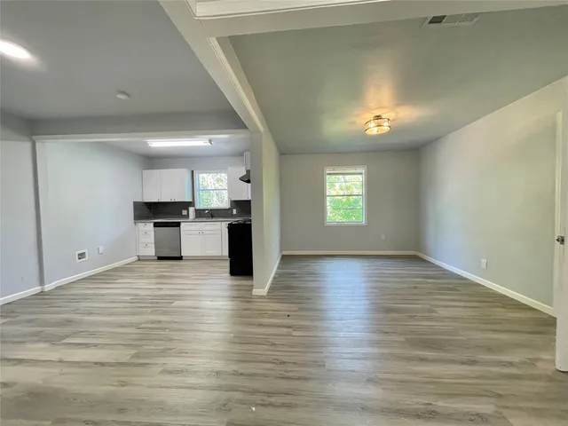 a view of empty room with kitchen and fireplace