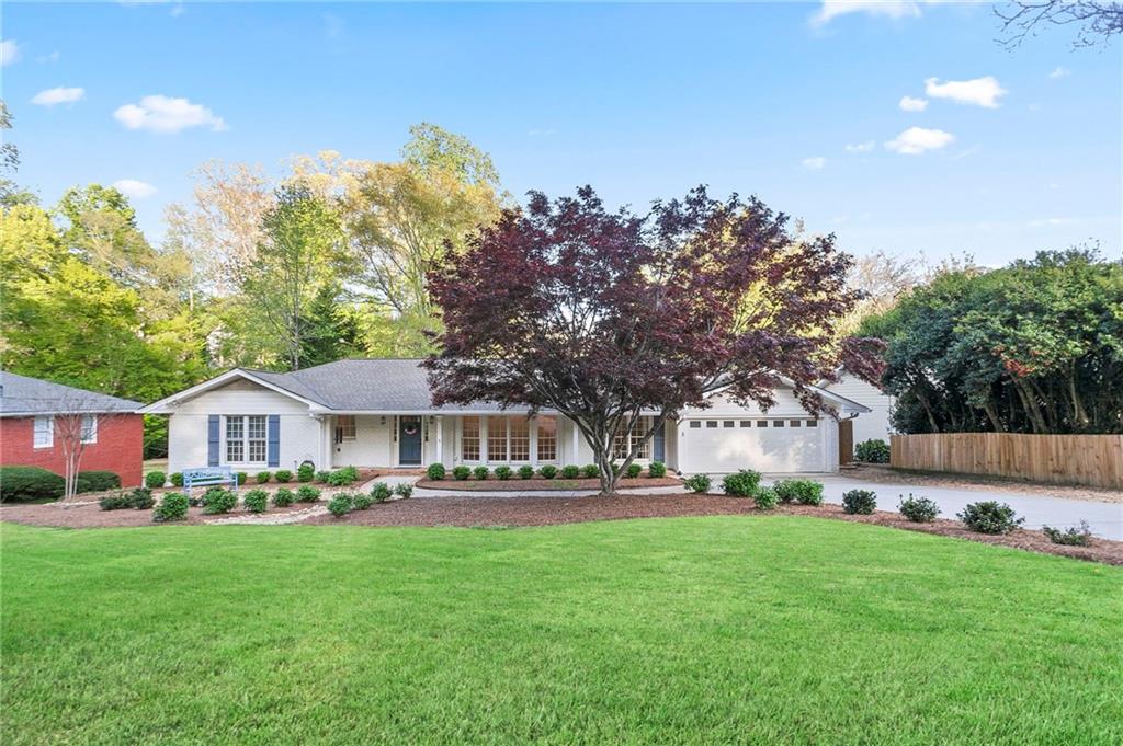 a front view of a house with a garden and trees