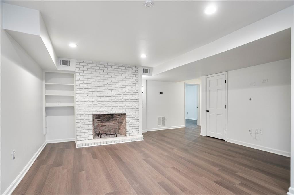 4555 Runnemede Road Northwest Atlanta, GA 30327 - Photo 25 of 51 an empty room with wooden floor and fireplace