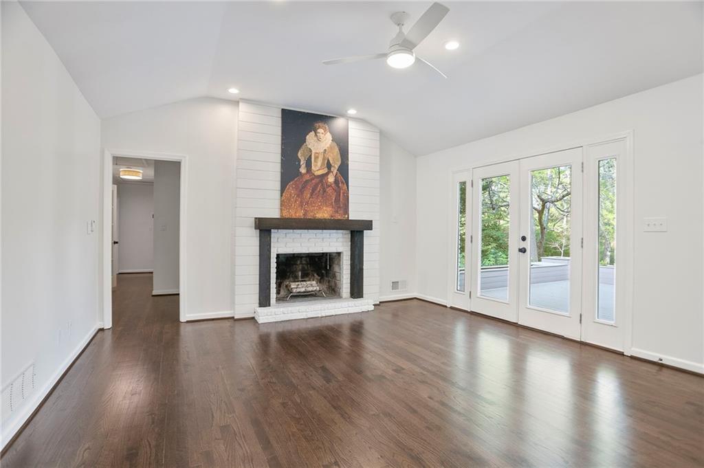 4555 Runnemede Road Northwest Atlanta, GA 30327 - Photo 8 of 51 an empty room with wooden floor fireplace and windows