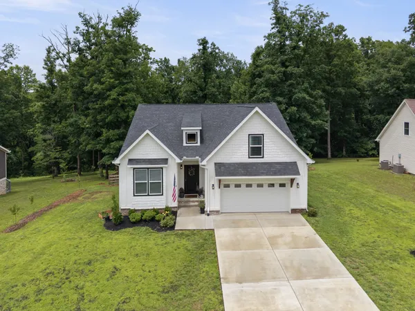 a front view of house with yard and trees in the background