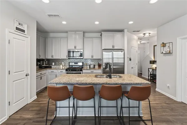 a kitchen with stainless steel appliances granite countertop a table chairs sink refrigerator and cabinets
