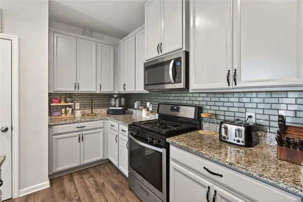 a kitchen with granite countertop cabinets stainless steel appliances and wooden floor