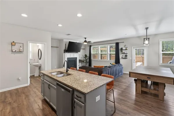 a open kitchen with stainless steel appliances granite countertop a kitchen island a stove a refrigerator a sink a dining table and chairs with wooden floor
