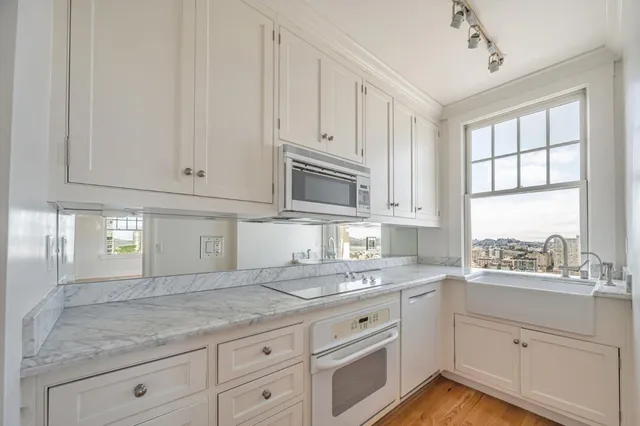 a kitchen with granite countertop white cabinets stainless steel appliances a sink and window