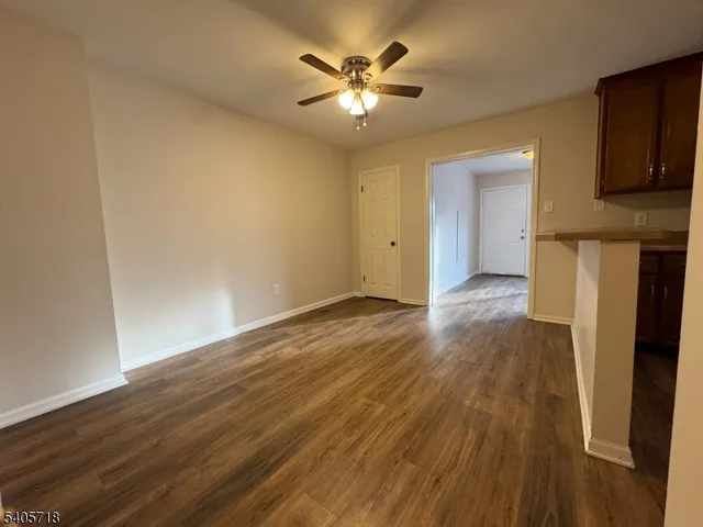 a view of an empty room with wooden floor and a ceiling fan