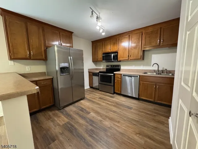 a kitchen with stainless steel appliances granite countertop a refrigerator a sink dishwasher a stove with wooden cabinets and floor