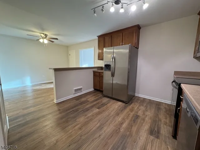 a kitchen with stainless steel appliances a refrigerator and a hard wood floor