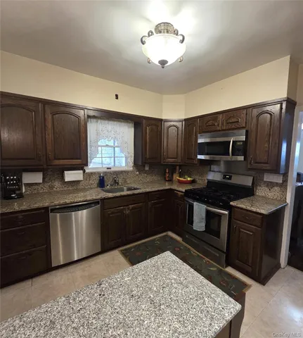 a kitchen with stainless steel appliances granite countertop wooden cabinets a stove top oven a sink and dishwasher