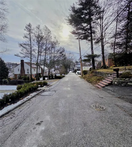 a view of a street with a bench and trees