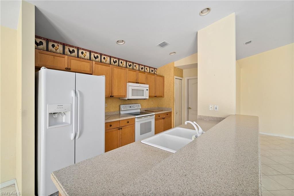 9281 Lanthorn Way Estero, FL 33928 - Photo 8 of 30 a kitchen with granite countertop a refrigerator and a stove top oven