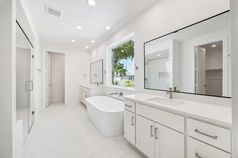 a spacious bathroom with a double vanity sink a mirror and a bathtub