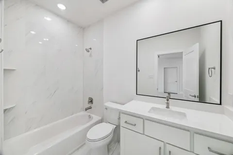 a bathroom with a toilet a sink a mirror a bathtub and vanity