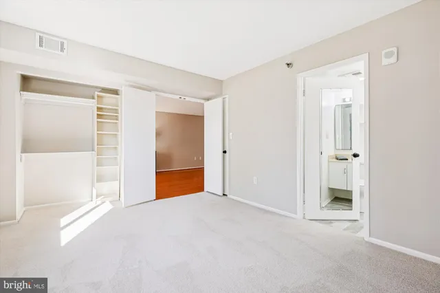 a view of an empty room with window and closet area