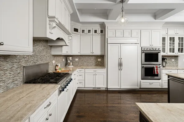 a kitchen with stainless steel appliances a refrigerator a stove a sink and white cabinets