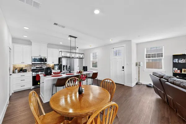 a living room with stainless steel appliances furniture a dining table and kitchen view