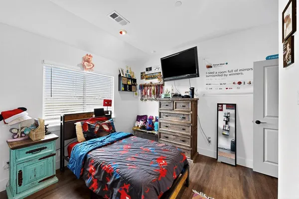 a bedroom with bed and a flat tv screen on dresser
