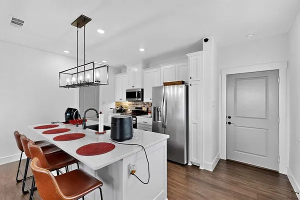 a kitchen with stainless steel appliances a dining table chairs refrigerator and sink