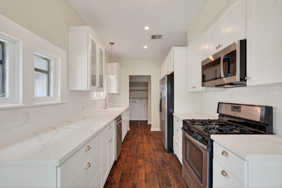 5401 North Capitol Street Houston, TX 77011 - Photo 23 of 39 a kitchen with stainless steel appliances granite countertop a stove top oven a sink dishwasher and a microwave oven with wooden floor