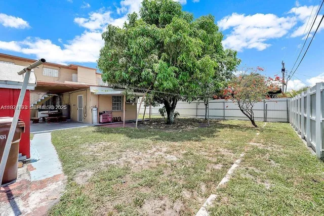 a view of a house with backyard and a tree