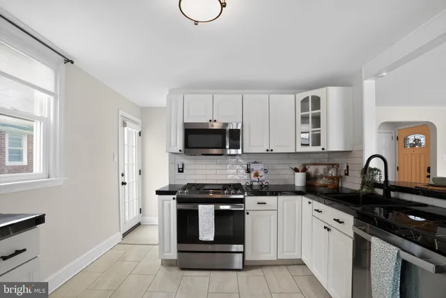 a kitchen with granite countertop a sink a stove top oven and cabinetry