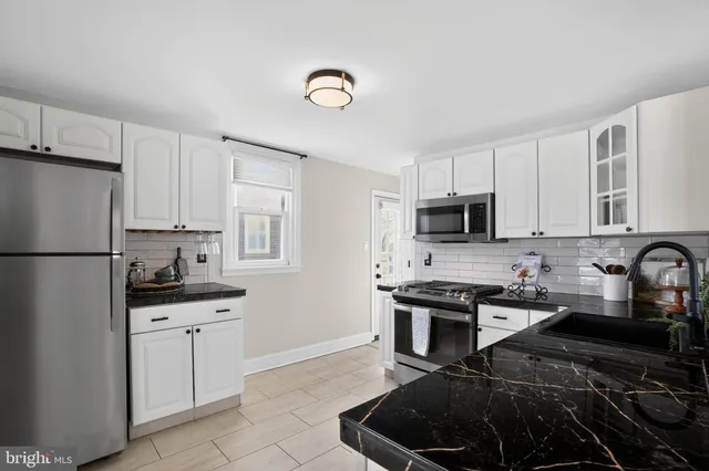 a kitchen with granite countertop a sink stove and refrigerator