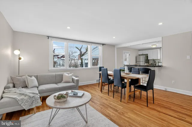 a living room with furniture and a dining table with wooden floor
