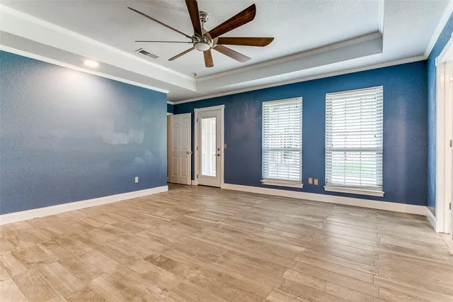 a view of an empty room with a window and wooden floor