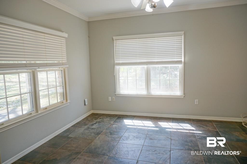 255 Suffolk Road Mobile, AL 36608 - Photo 21 of 29 Empty room featuring stone tile floors, crown molding, and ceiling fan