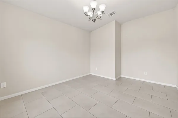 a view of an empty room with a chandelier fan