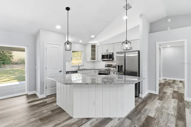 a kitchen with kitchen island a counter top space a sink appliances and a counter top space