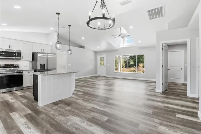 a view of kitchen with stainless steel appliances granite countertop cabinets and wooden floor