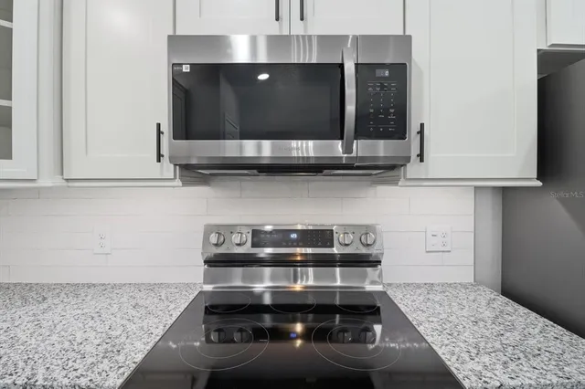 a kitchen with granite countertop a stove and a white cabinets
