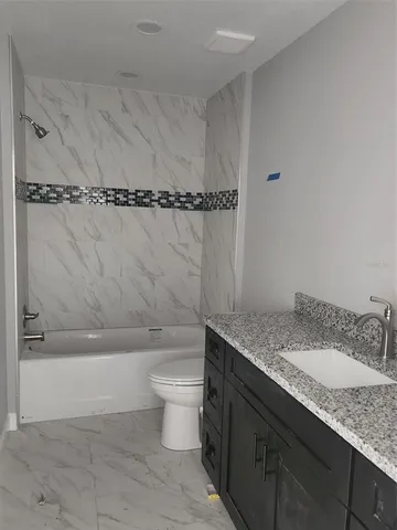 a bathroom with a granite countertop sink a toilet and bathtub
