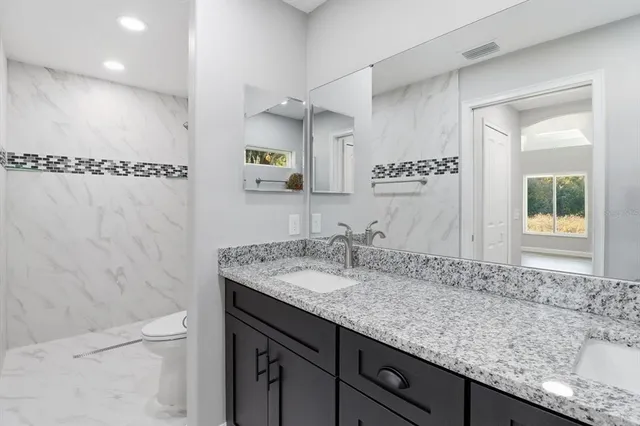 a bathroom with a granite countertop sink a mirror and a bathtub