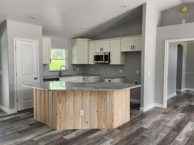 a kitchen with stainless steel appliances a sink a stove a refrigerator cabinets and a window