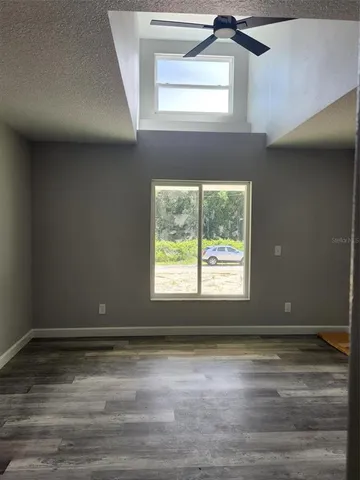 a view of a livingroom with an empty space a window and wooden floor