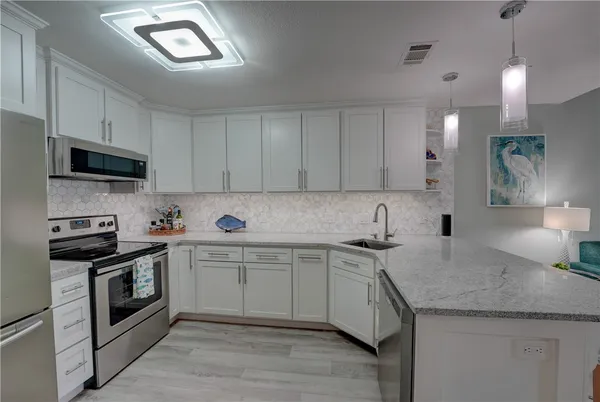 a kitchen with kitchen island granite countertop a sink stainless steel appliances and white cabinets