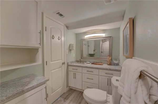 a bathroom with a granite countertop sink toilet a large mirror a vanity and shower