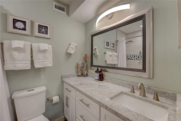 a bathroom with a granite countertop toilet sink and mirror